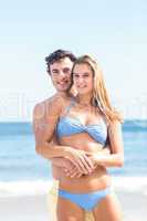 Happy couple in swimsuit looking at camera and embracing