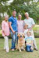 Happy family smiling at the camera with their dog