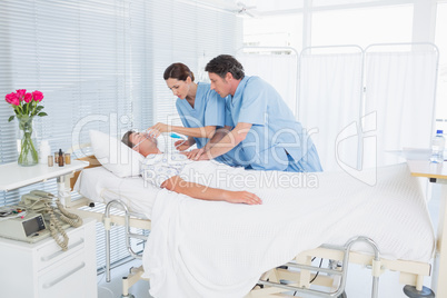 Worried doctors doing heart massage and holding oxygen mask