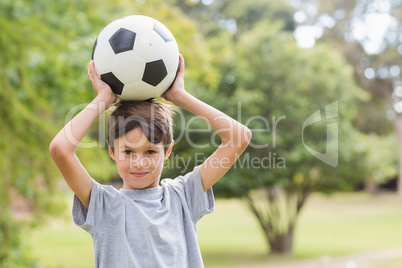 Smiling boy holding a soccer ball in the park