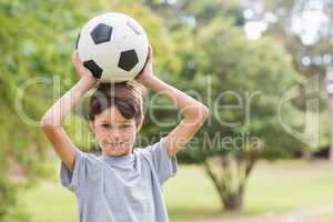 Smiling boy holding a soccer ball in the park