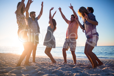 Happy friends dancing on the sand