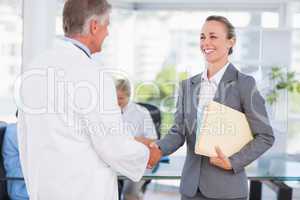 Confident doctor greeting pretty businesswoman