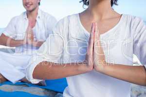 Happy couple doing yoga beside the water