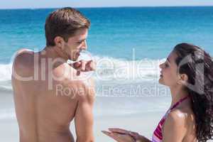 Pretty brunette putting sun tan lotion on her boyfriend