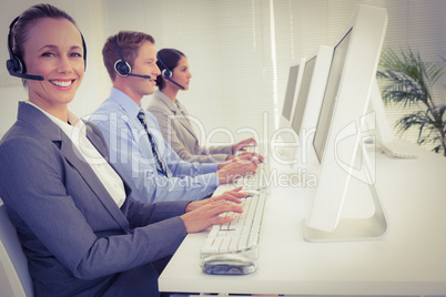 Business team working on computers and wearing headsets