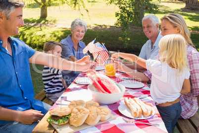 Happy family having picnic and holding american flag