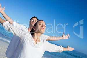 Happy couple doing yoga beside the water