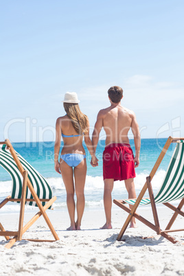 Happy couple holding hands and looking at the sea