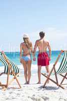 Happy couple holding hands and looking at the sea