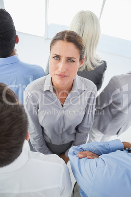 Unhappy businessman looking at camera with her colleague around