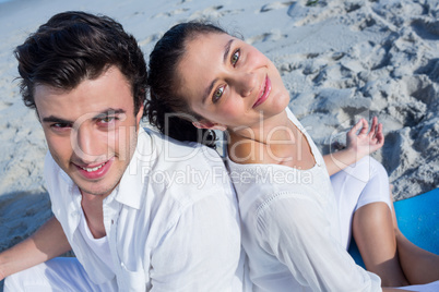 Happy couple doing yoga beside the water