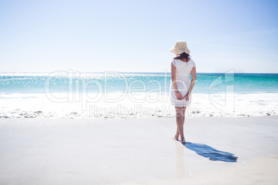 Pretty brunette wearing straw hat and walking in the water