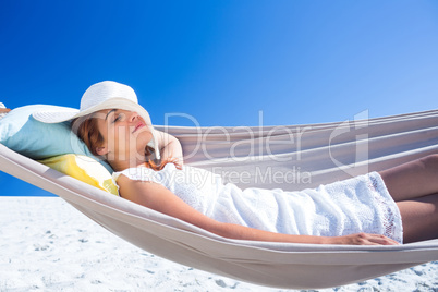 Pretty brunette relaxing with her straw hat in the hammock
