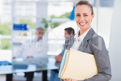 Smiling businesswoman holding files and looking at camera