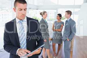 Businessman using tablet with colleagues behind him