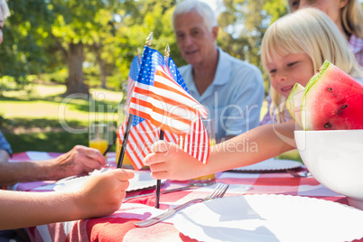 Happy family having picnic and holding american flag