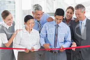 Business man cutting red strip