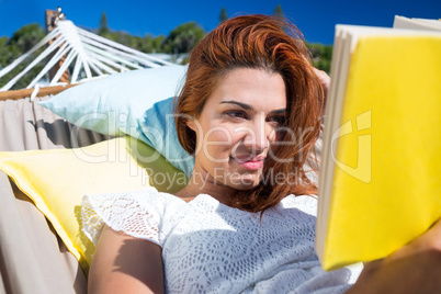 Brunette reading a book while relaxing in the hammock