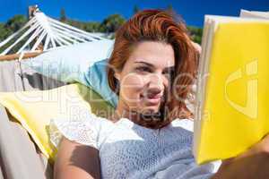 Brunette reading a book while relaxing in the hammock