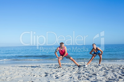 Happy couple stretching together beside the water