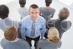 Businessman looking at camera and business team standing back to