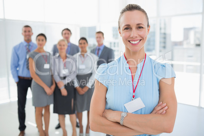 Businesswoman smiling at camera with team behind her