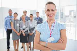 Businesswoman smiling at camera with team behind her