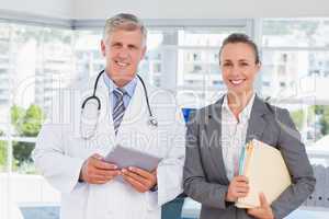 Confident doctor and pretty businesswoman smiling at camera