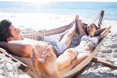 Happy couple relaxing together in the hammock and smiling at eac