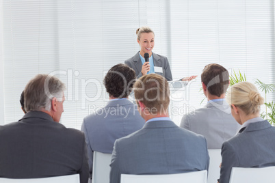 Pretty businesswoman talking in microphone during conference