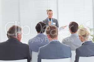 Pretty businesswoman talking in microphone during conference