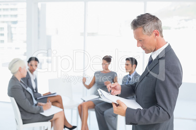 Businessman writing notes with colleagues behind