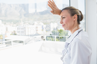 Confident female doctor looking through windows