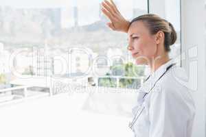 Confident female doctor looking through windows