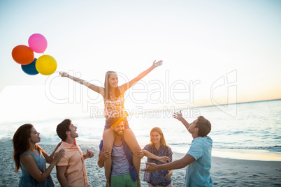 Happy friends dancing on the sand with balloon