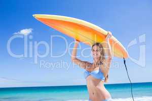 Pretty blonde woman holding surf board