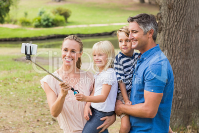 Happy family using a selfie stick in the park