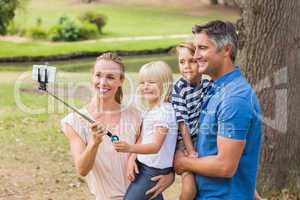 Happy family using a selfie stick in the park