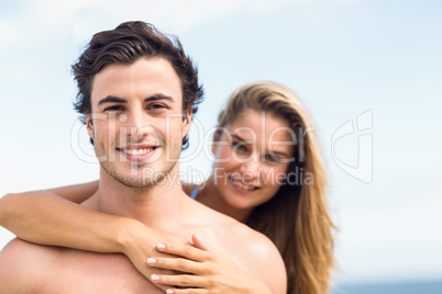 Happy couple in swimsuit looking at camera and embracing