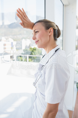 Confident female doctor looking through windows