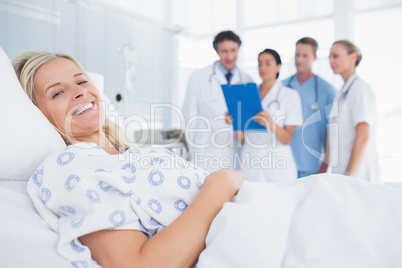 Smiling patient looking at camera with doctors behind