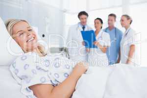 Smiling patient looking at camera with doctors behind