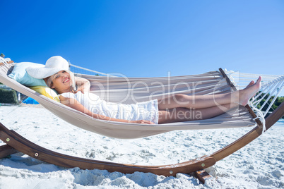 Pretty brunette relaxing with her straw hat in the hammock