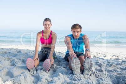 Happy couple stretching together beside the water