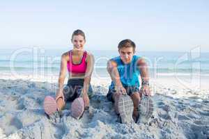 Happy couple stretching together beside the water