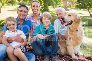 Happy family smiling at the camera with their dog