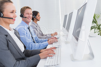 Business team working on computers and wearing headsets