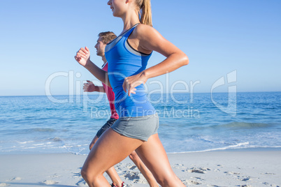 Happy couple running together beside the water