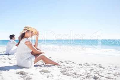 Brunette sitting in the sand and looking at the sea